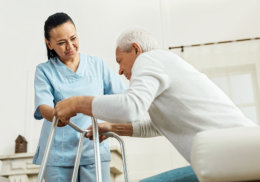 caregiver assisting senior man to get up on the walker