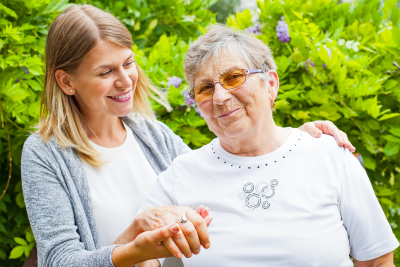caregiver and senior woman are smiling at outdoor